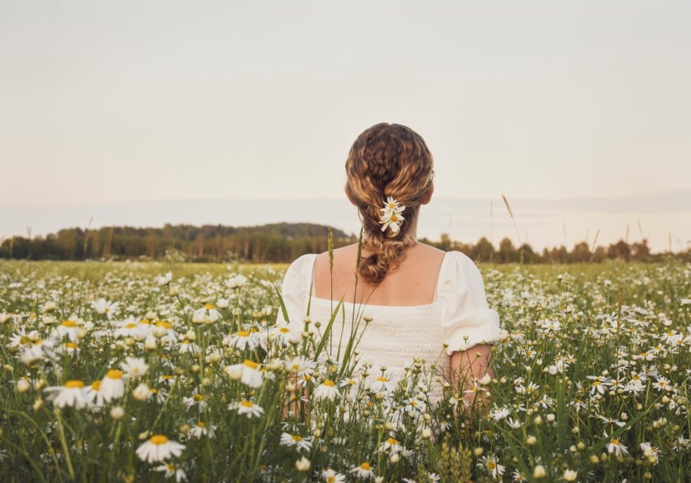 a woman in a field of flowers overcoming feelings of vulnerability